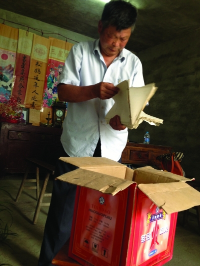 闵权的儿子在翻阅当年老人家保存下来的史料。